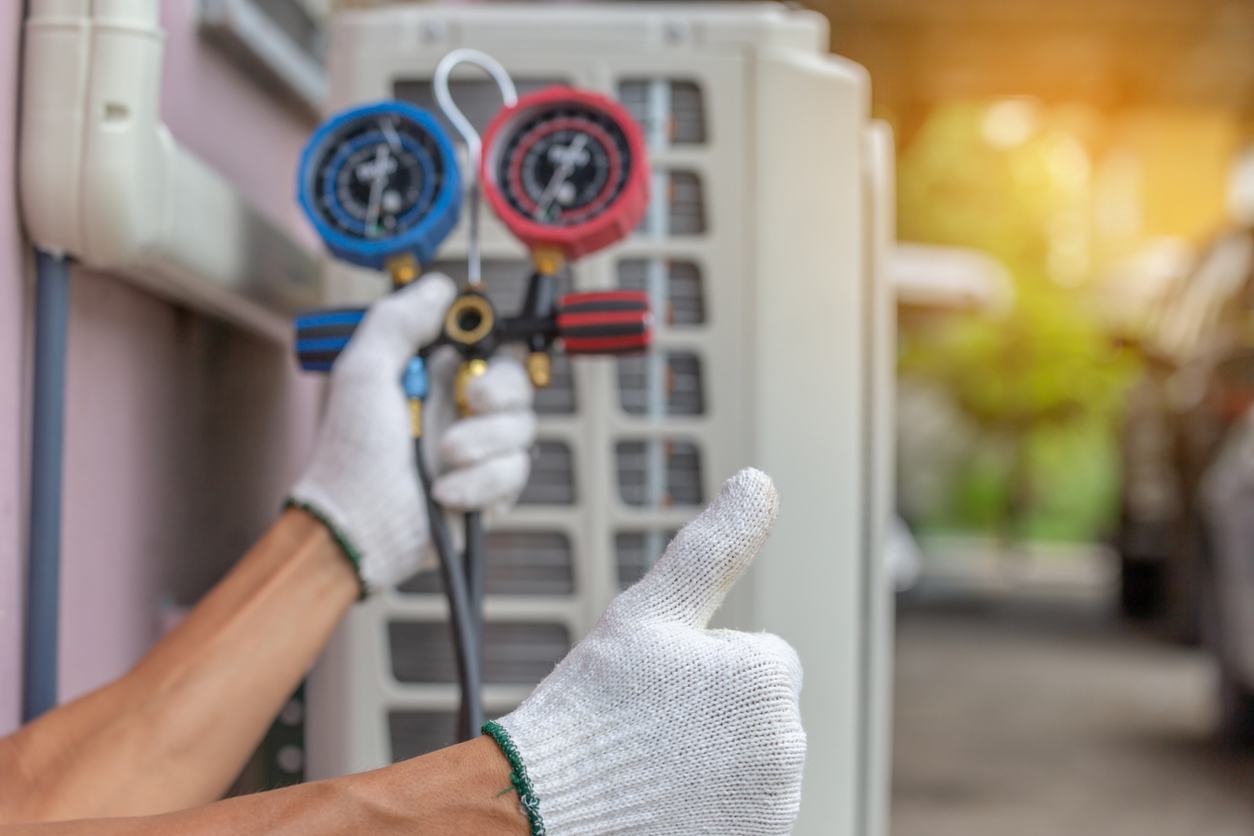 Air conditioning technician checking refrigerant levels and giving a thumbs up